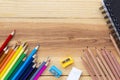 Many colored pencils with notebook on wood table. Royalty Free Stock Photo