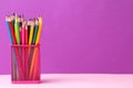 many colored pencils in a pink glass on a bright trendy lilac background. space for text Royalty Free Stock Photo