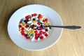 Many colored pills, medicine, capsules with powder in a white plate on a light background, the concept of maintaining health, Royalty Free Stock Photo