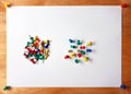 Many colored thumbtacks stuck into a white sheet of paper. attached to wooden board Royalty Free Stock Photo