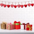 Many colorful gift boxes with ribbon bow on white table and white brick wall with vintage red heart shape garland. Valentines day Royalty Free Stock Photo