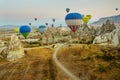 Many colorful hot air balloons flight above mountains - panorama of Cappadocia at sunrise. Wide landscape of Goreme valley Royalty Free Stock Photo