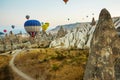 Many colorful hot air balloons flight above mountains - panorama of Cappadocia at sunrise. Wide landscape of Goreme valley Royalty Free Stock Photo