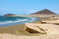 Many colorful kites on beach and kite surfers riding waves and flying during windy day in canarian El Medano in Tenerife with Royalty Free Stock Photo