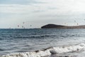 Many colorful kites on beach and kite surfers riding waves during windy day Royalty Free Stock Photo