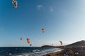 Many colorful kites on beach and kite surfers riding waves during windy day Royalty Free Stock Photo