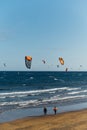 Many colorful kites on beach and kite surfers riding waves during windy day Royalty Free Stock Photo