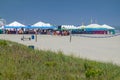 Many colorful large tents and a crowd of people on the beach near the ocean