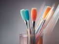 many colorful makeup brushes in glass cup