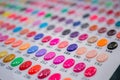 Many colorful palletes of gel nail polishes on counter of make up store