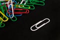 Many colorful paper clips lie on a black background paper Royalty Free Stock Photo