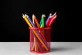 Many colorful pencils in holder on light table against black background Royalty Free Stock Photo