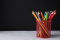 Many colorful pencils in holder on light table against black background, space for text Royalty Free Stock Photo