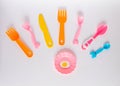 Many colorful plasic forks, spoons and knives on white background with copy space, top view. Devices for baby food Royalty Free Stock Photo