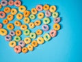 Many colorful round heart shaped sugary cereal grains on a blue background Royalty Free Stock Photo