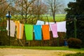 Many colorful towels, laundy are hanging on a clothing line in a county yard of an old farmhouse