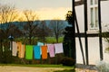 Many colorful towels, laundy are hanging on a clothing line in a county yard of an old farmhouse