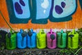 Colorful watering cans against the graffiti paint wall