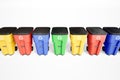 Many colorfull plastic garbage bins with recycling logo, staked on row.