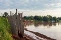 Many concrete columns form a long wall near the riverbank.