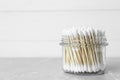 Many cotton buds in glass jar on light grey marble table, space for text Royalty Free Stock Photo