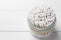 Many cotton buds in glass jar on white wooden table, space for text Royalty Free Stock Photo