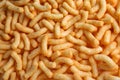 Many crunchy cheesy corn puffs as background, top view Royalty Free Stock Photo