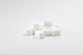 Many cubes of white regular sugar in a heap on a light background