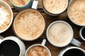 Many cups of different coffees on wooden table, flat lay