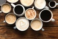 Many cups of different coffees on wooden table, flat lay