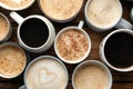 Many cups of different coffees on wooden table, flat lay