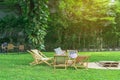 Many deck chairs and pillows with wooden table in the courtyard is surrounded by shady green grass. Comfortable pillows on outdoor