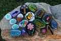 Many decorated painted rocks displayed on a small boulder