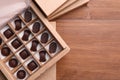 Many delicious chocolate candies in box on wooden table, top view and space for text. Production line Royalty Free Stock Photo