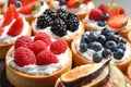 Many different berry tarts on table, closeup. Delicious
