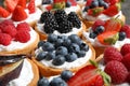 Many different berry tarts on table, closeup.