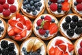 Many different berry tarts on , top view. Delicious pastries