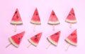 Many different bright ripe slices of watermelon on a stick on a bright pink background.