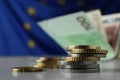 Many different coins on table against banknotes and European Union flag, closeup. Space for text Royalty Free Stock Photo