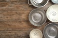 Many different colanders on wooden table, flat lay with space for text. Cooking utensils Royalty Free Stock Photo