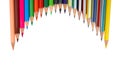 Many different colored wooden pencil crayons placed in a wave shaped row in front of a white background Royalty Free Stock Photo