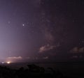 Many different constellations. Starry sky over the sea, the milky way and the lights of the night city. Light in the sky of a Royalty Free Stock Photo