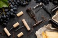 Many different corkscrews with open wine corks on dark concrete background in frame made of black grapes. Degustation winetasting