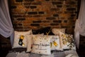 Many different decorative pillows on bed baldachin brick wall