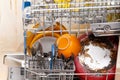 Many different dishes inside an open loaded dishwasher side view. Washing cutlery and various dishware simple concept, natural