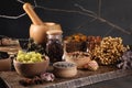 Many different dry herbs, flowers and mortar with pestle on black table Royalty Free Stock Photo