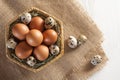 Many different eggs in basket and on burlap. White wooden background.