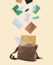 Many different envelopes falling into brown postman`s bag on beige background