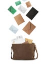 Many different envelopes falling into brown postman`s bag on white background