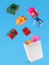 Many different gift boxes falling into paper shopping bag on light blue background Royalty Free Stock Photo